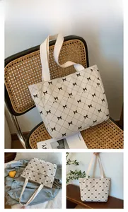 Detail of beige corduroy tote bag featuring black bow-knot print and woven handles