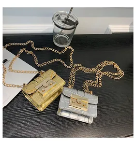 Close-up of mini croc-effect crossbody bags in gold and silver with chain straps