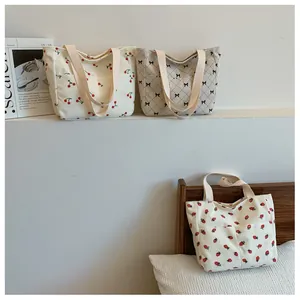 Detail of corduroy tote bags featuring cherry, strawberry, and checkered bow prints