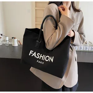 Detalle del bolso tote grande de lona negra con la inscripción blanca Fashion Paris