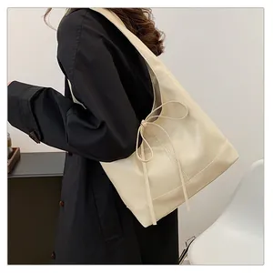 Detail van een crèmewitte grote draagtas met een minimalistisch strikontwerp op de tas