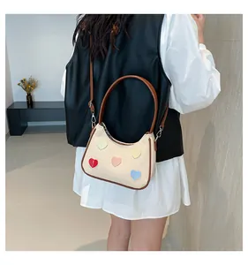 Vista posteriore di una modella con borsa in tela beige, cuori colorati e tracolla marrone