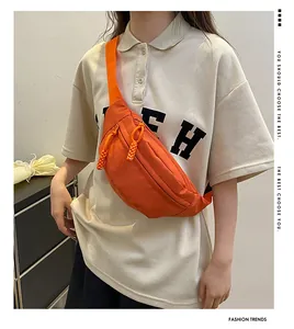 Detail view of the bright orange nylon chest bag with double zipper and woven pulls