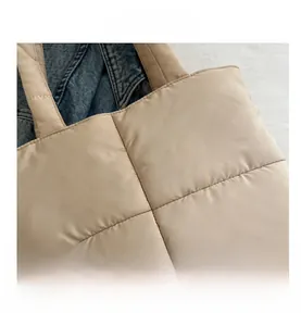 Close-up of beige quilted nylon tote bag with square embroidery on a textured background