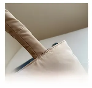 Close-up of fine stitching and quilted texture on the apricot puffer shoulder bag