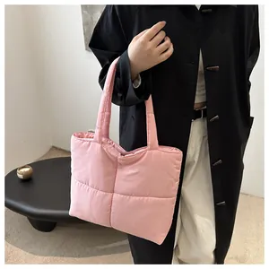 Pink quilted down tote bag with wide shoulder straps shown in a lifestyle model shot