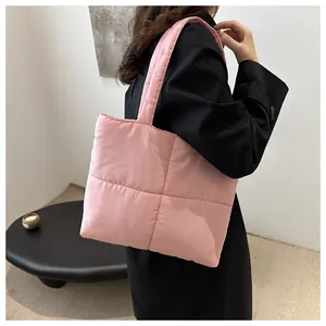 Close-up of pink quilted puffer tote bag with soft padded nylon finish on model