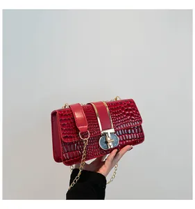 Macro shot of red crocodile texture handbag with gold chain strap and metal lock closure