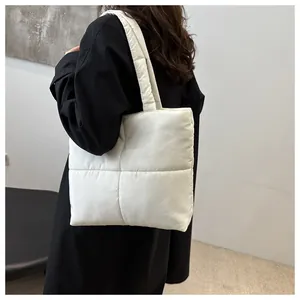 Detail of a white quilted puffer tote bag showing the soft padded nylon fabric texture