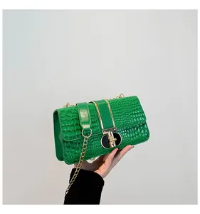 Detail of green crocodile texture faux leather bag with stylish gold and black metal lock