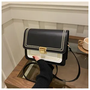 Detail of black and white crossbody bag with gold buckle and embroidery stitch accents
