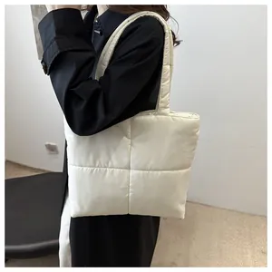Detail of a creamy white quilted nylon tote bag showing soft square padded embroidery