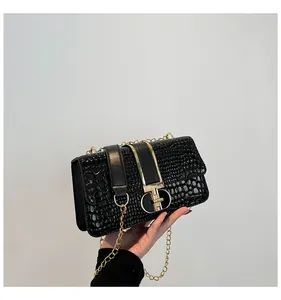 Detailed view of black crocodile pattern leather bag with elegant gold chain and clasp