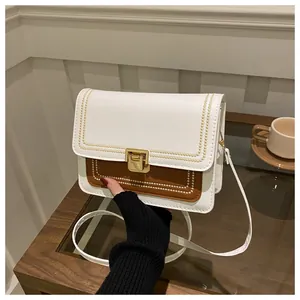 Detail of contrast stitch embroidery on white and brown PU leather crossbody bag