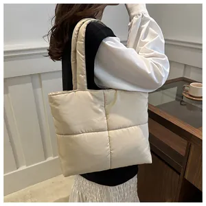 Quilted puffer tote bag in off-white shown on model in a modern interior setting