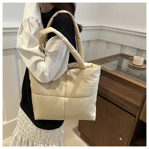 Close-up of beige quilted tote bag showing soft square texture and padded top handle