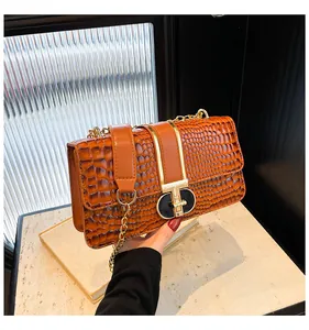 Close-up of brown crocodile texture faux leather with golden chain and T-bar lock