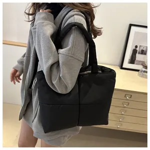 Close-up of quilted black nylon tote bag featuring soft down-filled square patterns