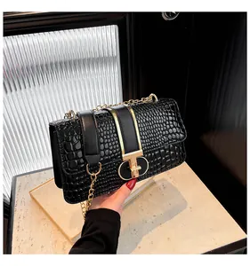 Detail of black crocodile-embossed leather texture and elegant gold T-bar metal clasp