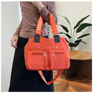 Detail van levendige oranje nylon crossbodytas met meerdere ritszakken en verstelbare riem