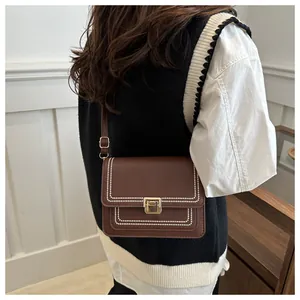 Close-up of retro brown crossbody bag with white stitched dots and gold twist lock