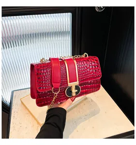 Detail of burgundy crocodile pattern leather bag with gold chain strap and metal lock