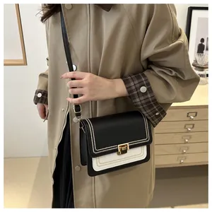 Detail shot of a black and white contrast crossbody bag with gold turn-lock on a model
