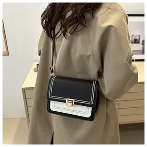 Detail of crossbody bag with black and white contrast stitching and gold bead trim