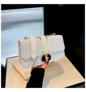 Detail of pearl white crocodile pattern bag with black and gold geometric metal lock