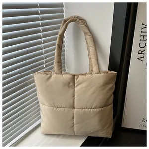 Close-up of khaki quilted puffer tote bag with large square stitching and soft padded handles