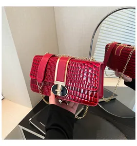 Detail of red croc-embossed leather handbag with luxury gold chain and clasp closure