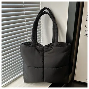 Detail of black quilted nylon tote bag showing soft puffy texture and large square pattern