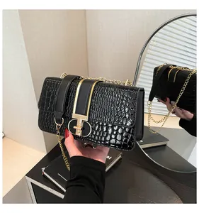 Close-up of black croc-embossed leather bag with gold metal buckle and mirror reflection