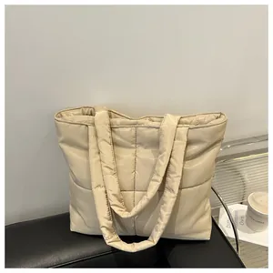 Detailed view of beige quilted down tote bag with soft square pattern on leather chair