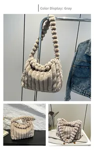 Detail of grey plush tote bag with vertical stripes and fluffy pom-poms on the shoulder strap