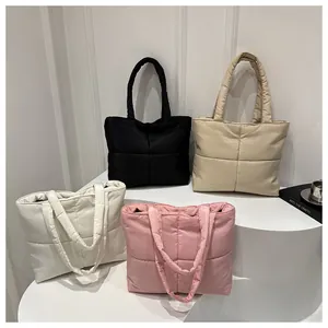 Quilted puffer tote bags in black, beige, pink and white on a minimalist stand