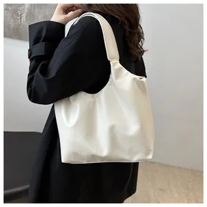 Side view of a minimalist cream hobo bag worn with a black coat for a stylish look