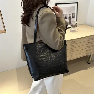 Minimalist black tote bag with embossed skeleton pattern on glossy leather surface