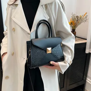 Fashionable black crocodile embossed leather handbag with golden buckle for women on white coat