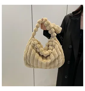 Close-up of beige plush tote bag with bubble texture and knotted handle on black coat