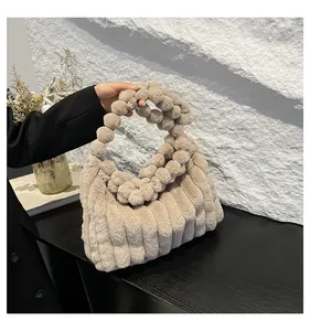 Close-up of khaki plush handbag featuring vertical striped texture and fuzzy ball handle
