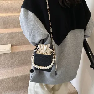 Mini-Beuteltasche in Schwarz mit Perlengriff und Kordelzug-Futter am Modell gezeigt
