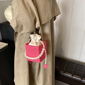 Rosa karierte Beuteltasche mit Perlengriff und Kordelzugfutter passend zum Trenchcoat-Outfit