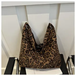 Detail of leopard print tote bag with metal eyelets on a minimalist leather chair