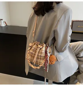 Détail du sac seau en tweed à carreaux avec cordon de serrage et poignée tressée