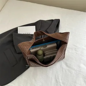 Brown woven leather tote bag with magnetic closure shown on a blazer backdrop