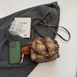 Sac seau rétro à carreaux marron avec peluche sur un blazer gris, style automne