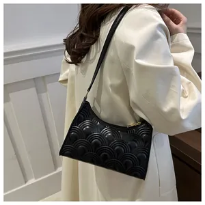 Detail of black quilted underarm bag with shell pattern stitching and gold zipper