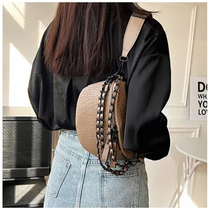 Détail du sac bandoulière avec motif crocodile et bandoulière chaîne noire
