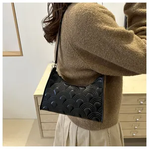 Detail of black underarm bag featuring fan-shaped quilted pattern and glossy leather